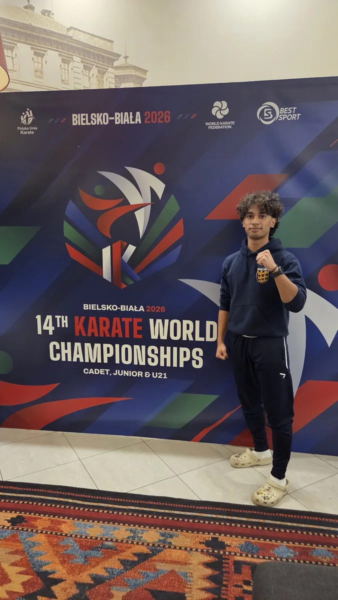 Kobe in his England hoodie in front of the 14th Karate World Championships banner in Bielsko-Biała, Poland